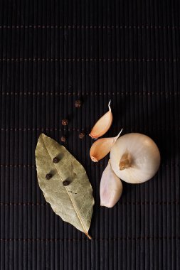 soğan, sarımsak, kara biber ve defne yaprağı siyah bir zemin üzerine