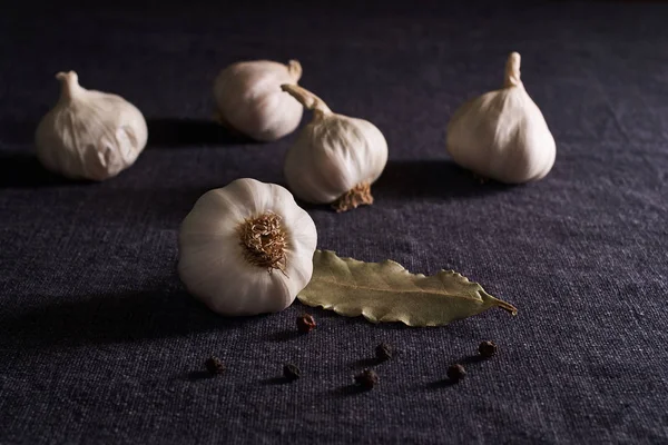 Garlic, onion, bay leaf, black pepper on textile background. Food background. Garlics. sliced garlic, garlic clove, garlic bulb.