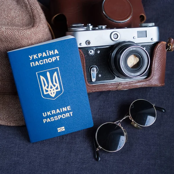 Ukrayna pasaportu gri arka plan üzerinde seyahat. güneş gözlüğü, şapka. arka planda Vintage fotoğraf makinesi. AB vize ücretsiz erişim. Sığ derinlik-in tarla, pasaport Ukraynalı logosuna odaklanmak.