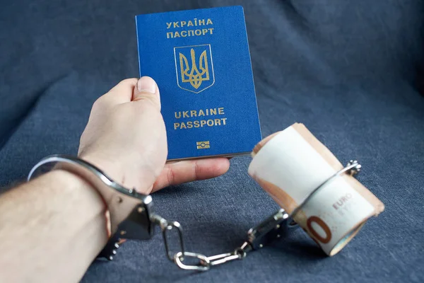 Ukraiński paszport biometryczny i kajdanki na stole. — Zdjęcie stockowe
