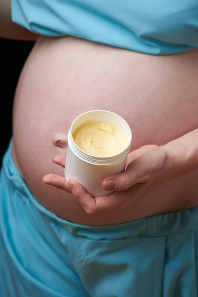 Glad gravid kvinna med magkräm. Förebyggande av bristningar. Graviditet och hudvård. mage gravid kvinna och leende från fuktgivande kräm för bristningar — Stockfoto