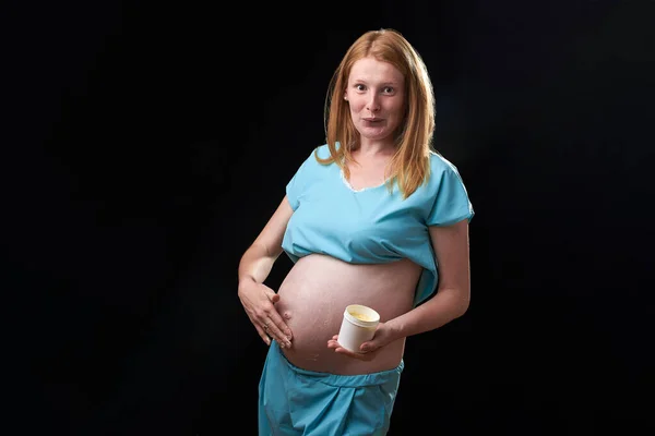 Glad gravid kvinna med magkräm. Förebyggande av bristningar. Graviditet och hudvård. mage gravid kvinna och leende från fuktgivande kräm för bristningar — Stockfoto