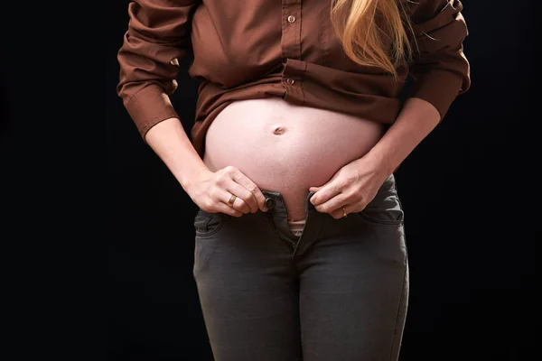 Het ongemak van zwangerschap. Een zwangere vrouw kan haar broek niet vastmaken. zwaarte van de bewegingen van de zwangere vrouw — Stockfoto