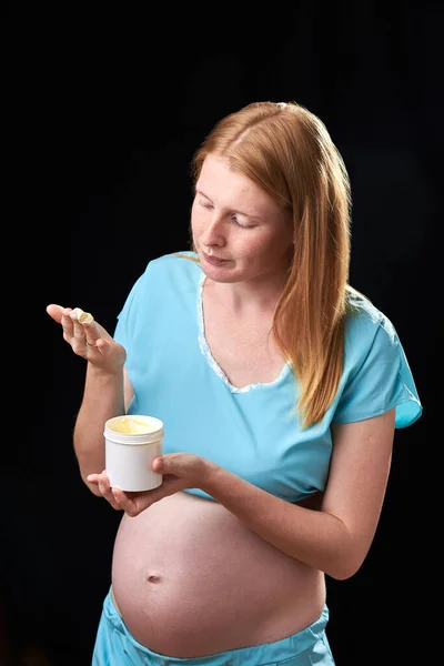 Heureuse femme enceinte avec crème de ventre. prévention des vergetures. Grossesse et soins de la peau. ventre de la femme enceinte et sourire de crème hydratante pour les vergetures — Photo