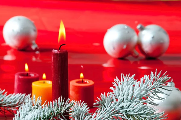 Brandende kaarsen met Kerstmis takje op de rode achtergrond — Stockfoto