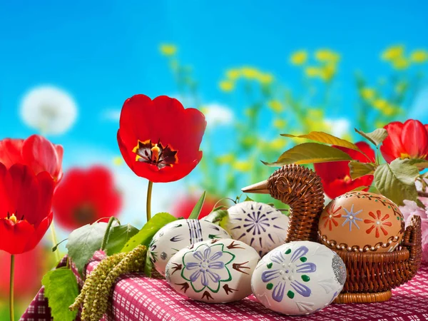 Huevos de Pascua pintados con tulipanes rojos en la cama de flores —  Fotos de Stock