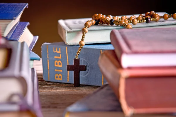 Bibel und Holzrosenkranz im Bücherregal — Stockfoto