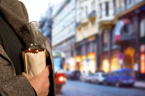 Drinker hiding bottle of spirits in the paper bag — Stock Photo, Image