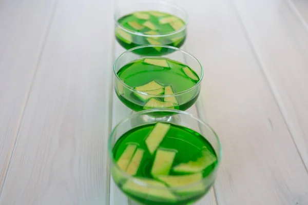 Green jelly in transparent slippers on a white wooden background