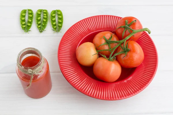 Guisantes verdes, jugo de tomate y una rama de tomates sobre un fondo blanco — Foto de Stock