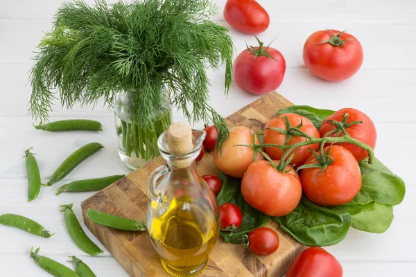 Aceite de oliva, perejil, espinacas, guisantes verdes y una rama de tomates sobre un fondo blanco — Foto de Stock