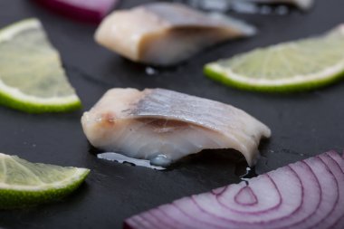 Soğan ve kireç ile ringa balığı üzerinde siyah arduvaz kaplamak dilimlenmiş