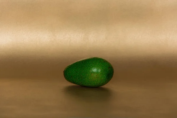 Ganze Avocado Auf Goldenem Hintergrund — Stockfoto