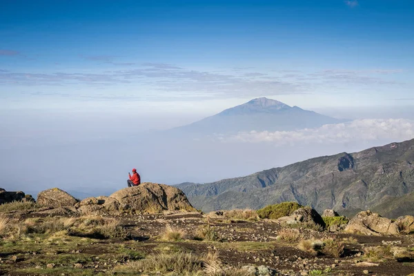 Hombre sentado con su teléfono en las montañas — Foto de Stock