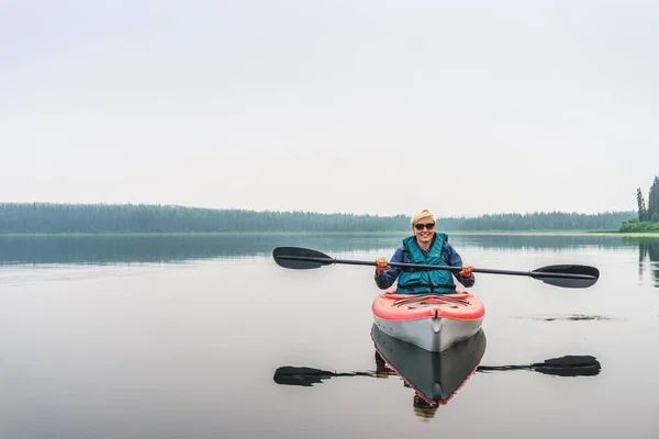 Frau mit Sonnenbrille genießt den See aus rotem Kajak — Stockfoto