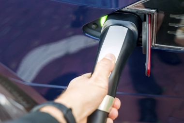 Modern elektrikli araba şarj çıkış tutan adamın el.