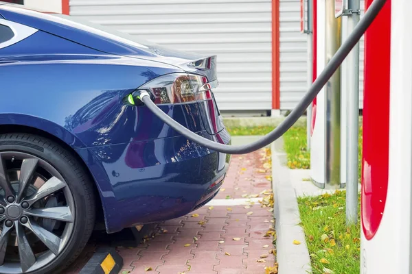 Moderne elektrische auto die zijn aangesloten op het laadstation op een parkeerplaats — Stockfoto