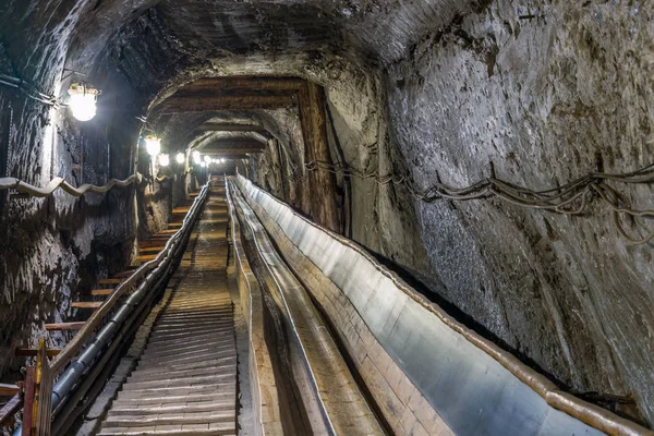 Bälte conveyot i belysta underjordisk tunnel — Stockfoto