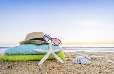 Güneş gözlüğü, havlu, şapka, güneş kremi, kabukları ve denizyıldızı sandy üzerinde