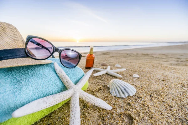 Óculos de sol, toalhas, chapéu, protetor solar, conchas e estrelas do mar em arenoso — Fotografia de Stock