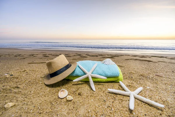 Occhiali da sole, asciugamani, cappello, crema solare, conchiglie e stelle marine su sabbia — Foto Stock