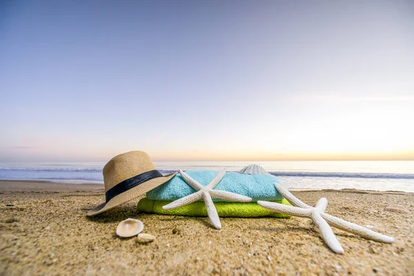 Zonnebril, handdoeken, hoed, zonnebrandcrème, schelpen en zeesterren op sandy — Stockfoto