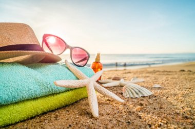 Güneş gözlüğü, havlu, şapka, güneş kremi, kabukları ve denizyıldızı sandy üzerinde