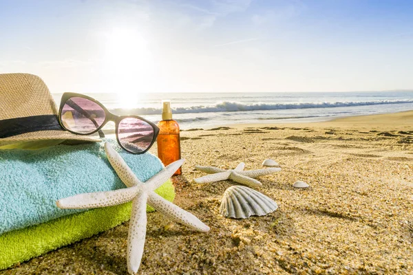 Óculos de sol, toalhas, chapéu, protetor solar, conchas e estrelas do mar em arenoso — Fotografia de Stock