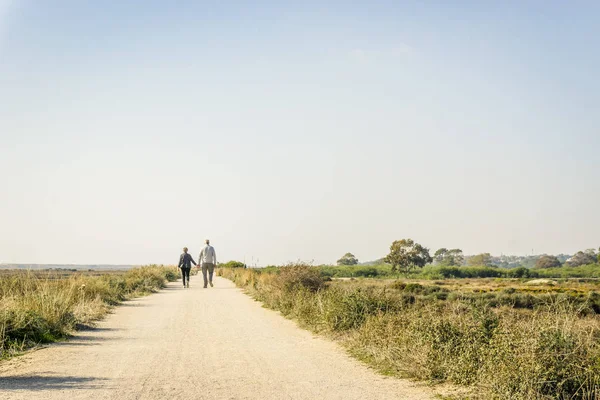 Casal de idosos apaixonados a caminhar numa estrada de poeira, Portugal — Fotografia de Stock