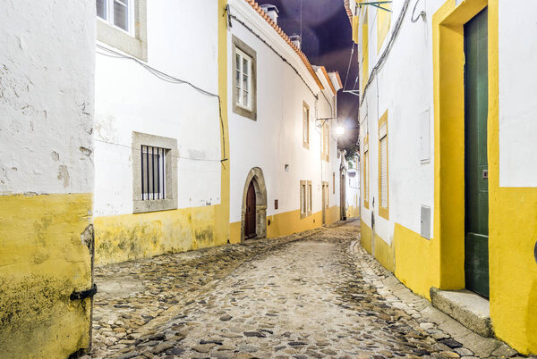 Narrow street with white and yellow houses by night in Evora, Alentejo, Portugal