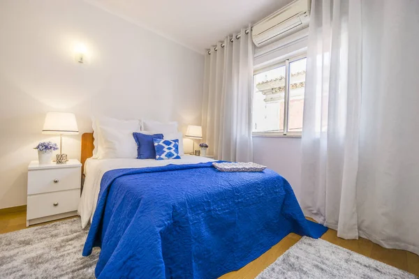 An elegant bedroom arranged in white and blue with turn on light — Stock Photo, Image