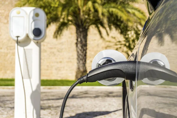 Electric car plugged by cable to charging station — Stock Photo, Image