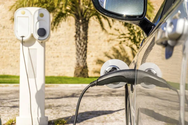 Electric car plugged by cable to charging station — Stock Photo, Image