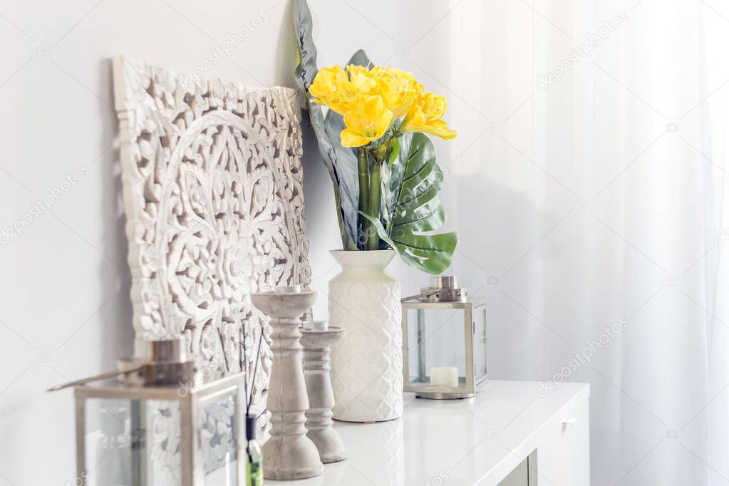 Yellow flowers in ceramic vase with wooden candlesticks and lant