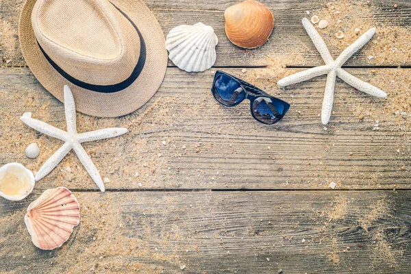 Sommaren hatt, skal och sol glasögon på trä och sandstranden bak — Stockfoto