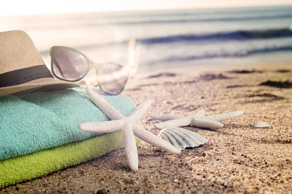 Serviettes colorées, chapeau de paille, lunettes de soleil et coquillages sur le sable — Photo