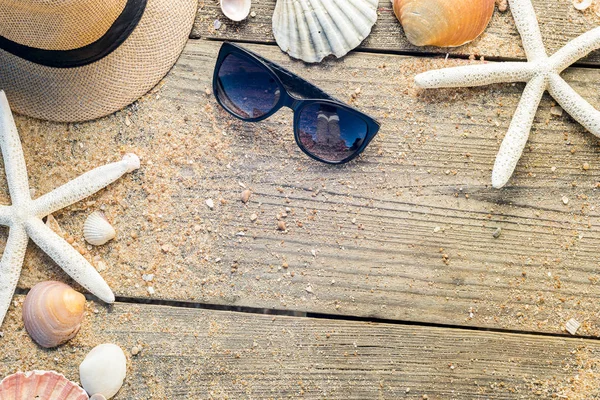 Chapéu de verão, conchas e óculos de sol em backgroun de madeira e areia — Fotografia de Stock