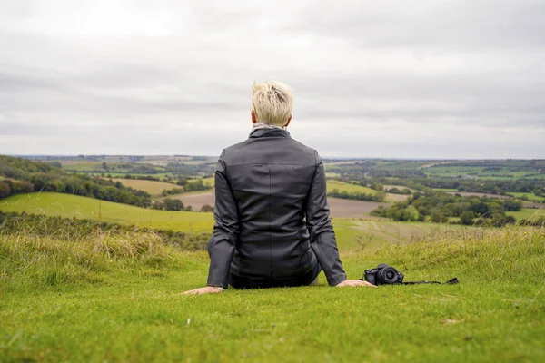 Femme blonde avec caméra contemplant paysage verdoyant vallonné — Photo