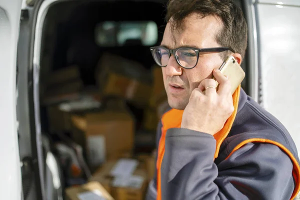 Delivery man talking on the phone in front of his car f — Stock Photo, Image