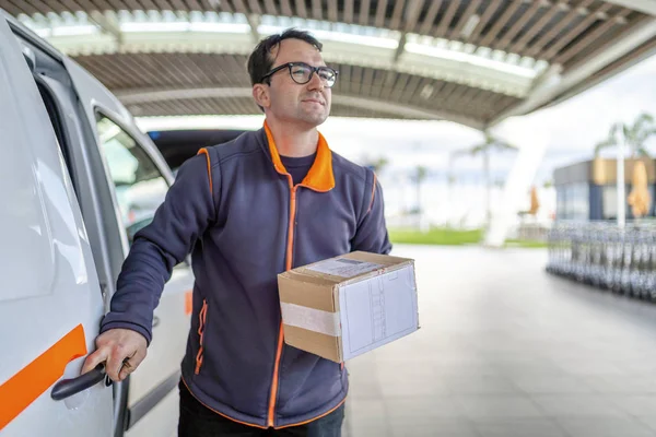 Bezorger verlaat zijn auto met een pakje — Stockfoto