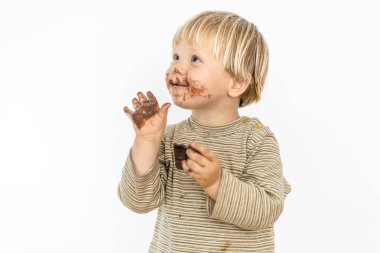 Beyaz arka planda izole edilmiş, büyük bir zevkle çikolata yiyen tatlı sarışın bebek.