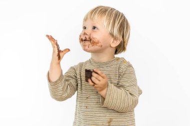 Beyaz arka planda izole edilmiş, büyük bir zevkle çikolata yiyen tatlı sarışın bebek.