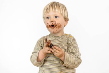 Beyaz arka planda izole edilmiş, büyük bir zevkle çikolata yiyen tatlı sarışın bebek.
