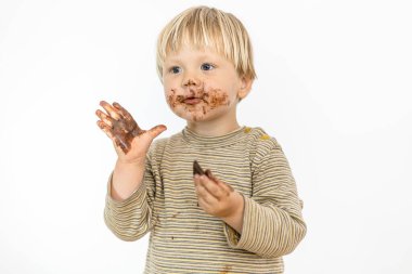 Beyaz arka planda izole edilmiş, büyük bir zevkle çikolata yiyen tatlı sarışın bebek.