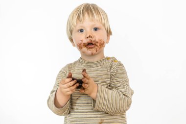 Beyaz arka planda izole edilmiş, büyük bir zevkle çikolata yiyen tatlı sarışın bebek.