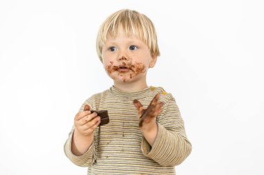 Beyaz arka planda izole edilmiş, büyük bir zevkle çikolata yiyen tatlı sarışın bebek.