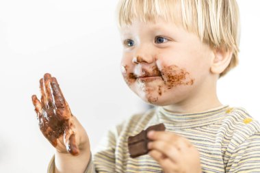 Beyaz arka planda izole edilmiş, büyük bir zevkle çikolata yiyen tatlı sarışın bebek.
