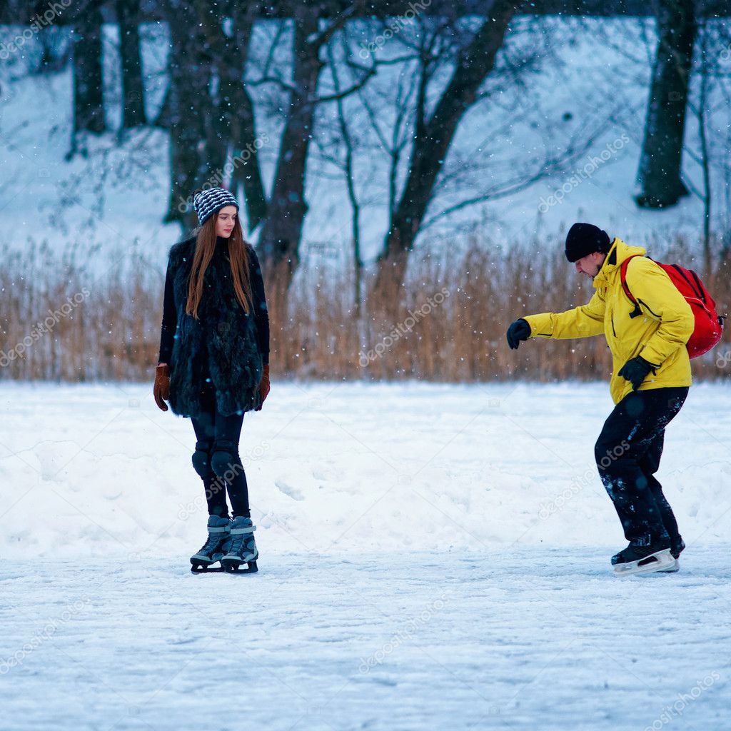 Young girl and fellow ice skating in winter Trakai