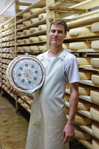 Trabalhador segurando uma roda de queijo em Franche Comte laticínios — Fotografia de Stock