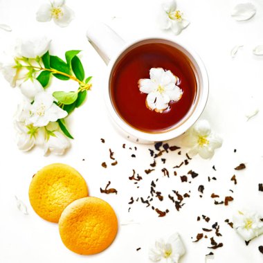 Çay bardağı kurutulmuş ve taze Yasemin çiçekleri ve çerezler ile